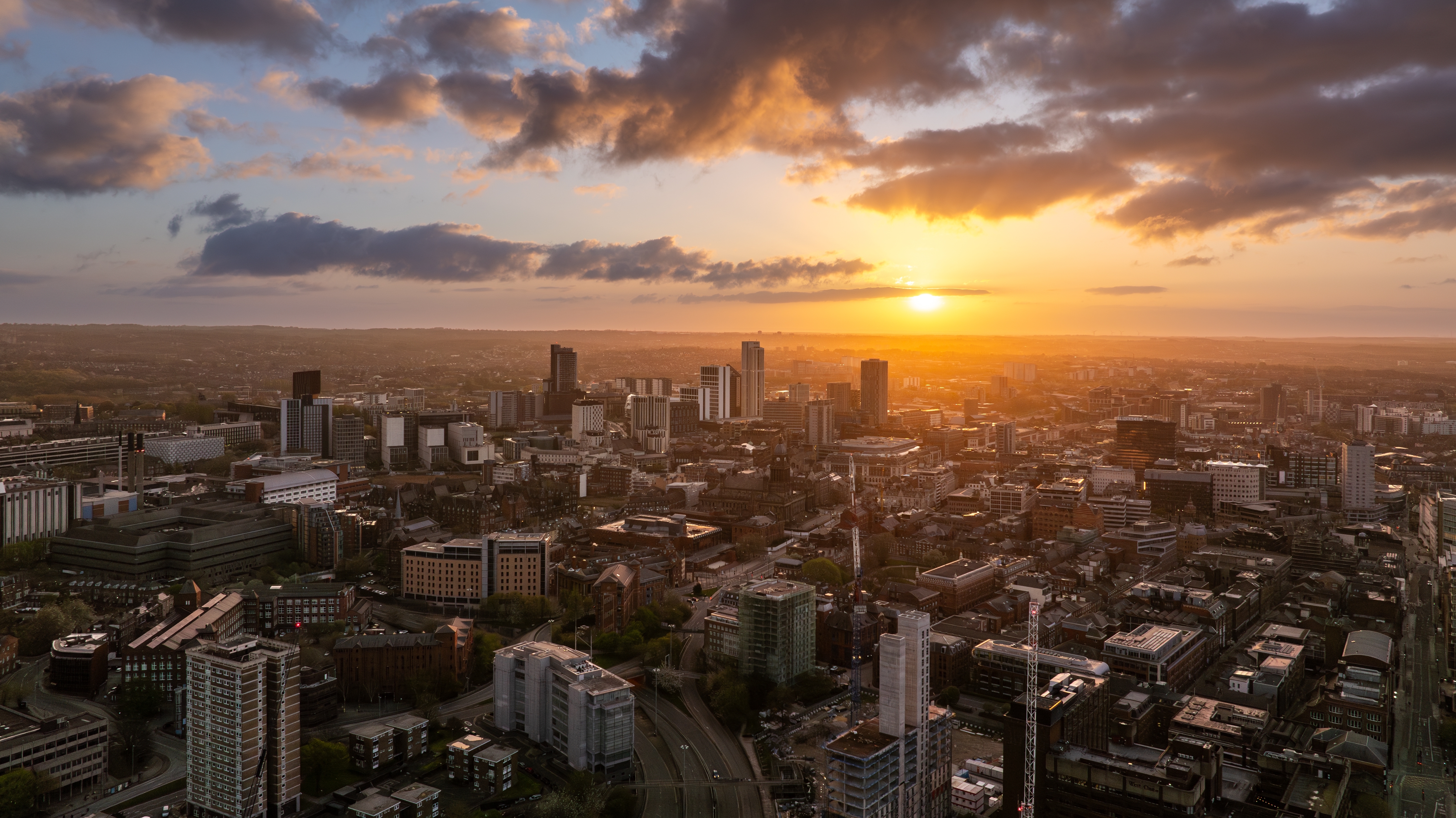 drone shot of Leeds city centre with golden sunset