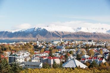 Colourful buildings of Reykjavik, the capital of Iceland, backed by a lake and snowy mountains